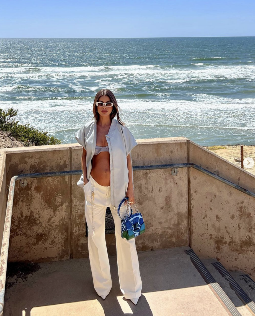 Model standing in wide leg white pants against beach background